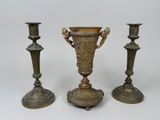 trois vases en laiton vieilli posés les uns à côté des autres sur une surface blanche