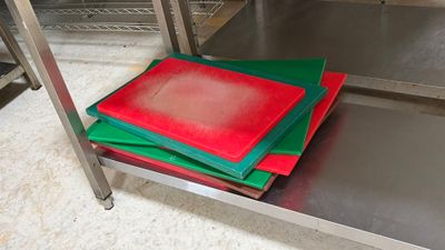 several pieces of red and green cutting mats on a metal shelf
