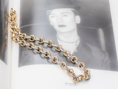 un livre auquel est attachée une chaîne et sur lequel figure l'image d'une femme coiffée d'un chapeau