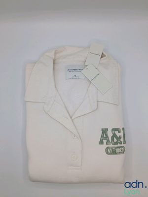 polo blanc avec un logo vert et blanc sur la poitrine