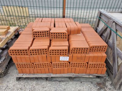 un tas de briques posé sur une palette devant une clôture