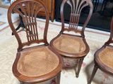 three wooden chairs sitting on a rug in a living room
