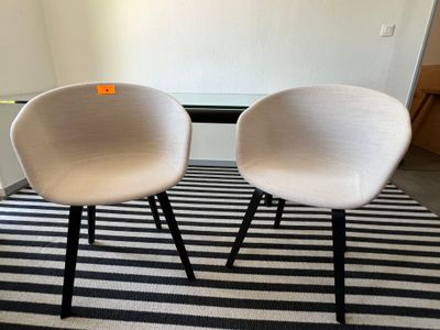 deux chaises blanches posées sur un tapis rayé noir et blanc