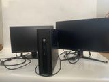 two computer monitors sitting on top of a table next to each other