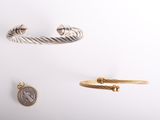 trois types de bracelets différents et une pièce de monnaie posés sur une surface blanche