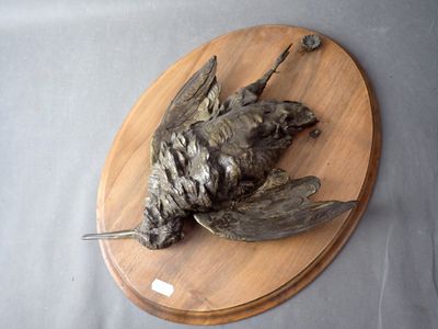 a bronze bird on a wooden plaque on a table