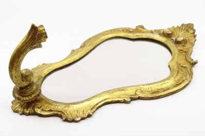 a gold mirror with a bird on it on a white surface