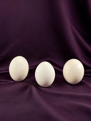 three white eggs sitting on top of a purple cloth