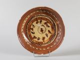 une assiette marron et blanche posée sur un socle, sur laquelle se trouve une horloge