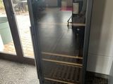 a wine cooler in the corner of a room next to a window