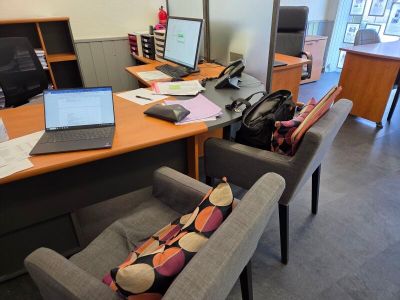a desk with two chairs and a laptop on top of it