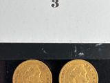 a pair of gold coins sitting on top of a black table