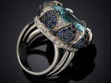 a close up of a ring with blue and white diamonds on a black surface