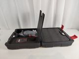 une valise noire ouverte, munie d'une poignée rouge, posée sur une table blanche