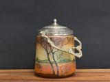 a small jar with a tree on it on a table