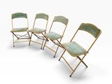 quatre chaises pliantes alignées sur une surface blanche