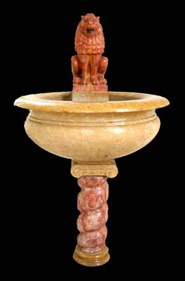 une statue représentant un lion assis au sommet d'une fontaine