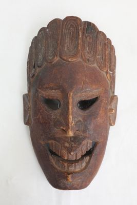 un vieux masque en bois accroché à un mur blanc