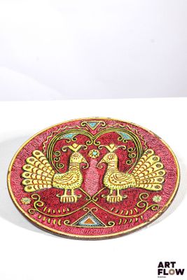 assiette rouge et dorée ornée de deux oiseaux sur un fond blanc