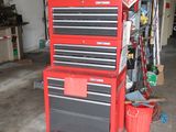 a garage with a red tool cabinet and a black and red tool box