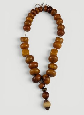 un collier en perles de bois dont l'extrémité est ornée d'un pompon