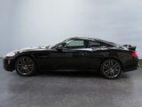 a black sports car is parked in a room with a gray wall