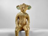 une figurine en or représentant un singe assis sur une surface blanche