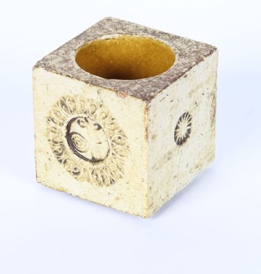 a small square vase that has a lion on it