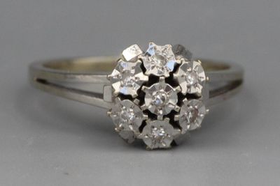 une image d'un anneau en forme de grappe de diamants sur un fond blanc