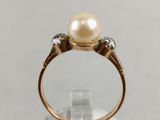 a close up of a ring with a pearl and diamonds on it