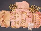 un sac rose avec des boutons dorés et un tas de boules dorées