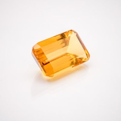 an orange sapphire stone on a white surface