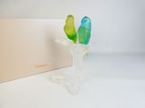 un vase en verre orné de deux oiseaux, à côté d'une boîte
