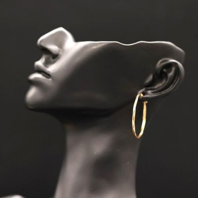 a close up of a mannequin head wearing a pair of gold hoop earrings