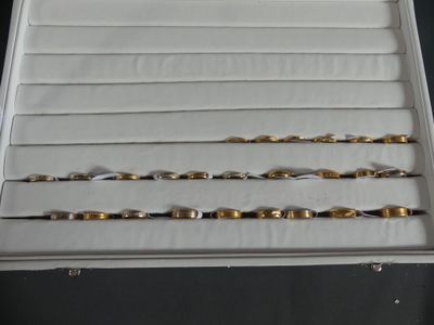 three pairs of gold and silver bracelets in a white box