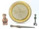 a gold plate with a design on it next to a knife and a figurine