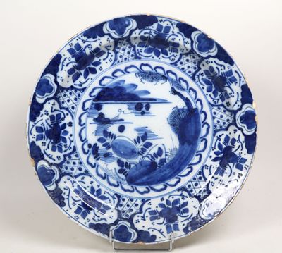 une assiette bleue et blanche ornée d'un oiseau, posée sur un socle