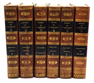 six vieux livres sont alignés sur une surface blanche