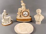 trois statues et une horloge exposées sur une table