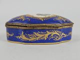 an antique blue and gold box sitting on top of a white table