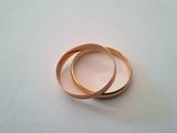 two gold wedding rings on a white surface
