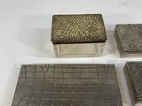four pieces of silver and black tile on a white surface