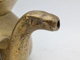 a gold teapot with a handle on a white table