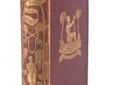 an old book with a gold design on it sitting on a white surface
