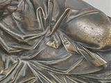 a bronze statue of a woman laying on a pillow