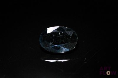 a close up of a blue diamond on a black surface