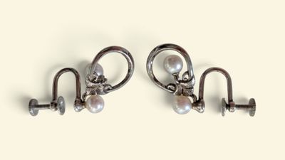 two pairs of silver earrings with pearls hanging from them on a white surface