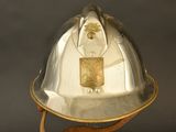 a silver fire helmet with a gold emblem on it