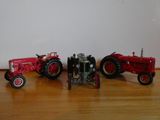 three toy tractors that are sitting on a wooden floor