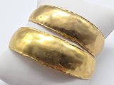 two gold plated rings on a white napkin on a white surface